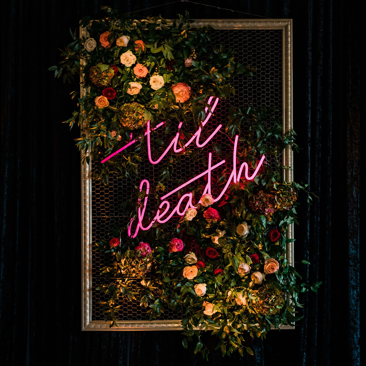 flower wall with neon sign wedding til death